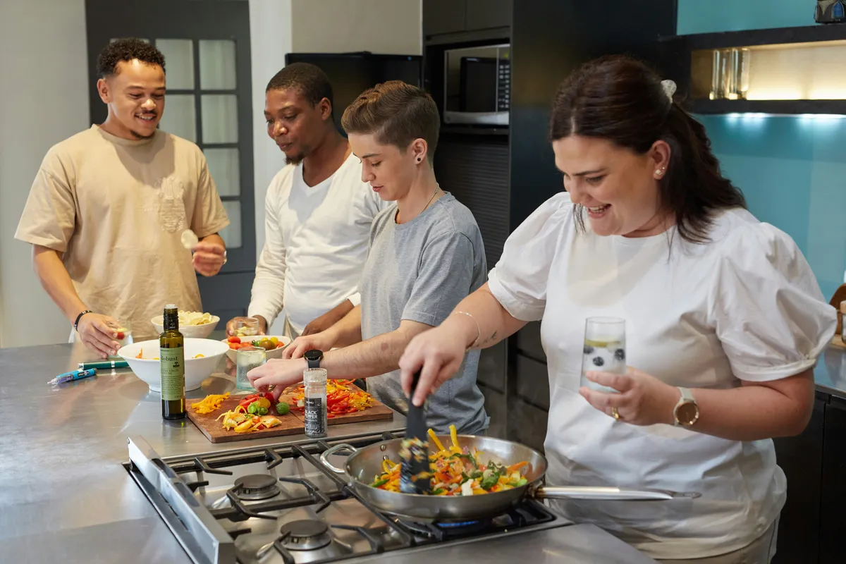 Four friends cooking an ordinary dinner together in a home kitchen