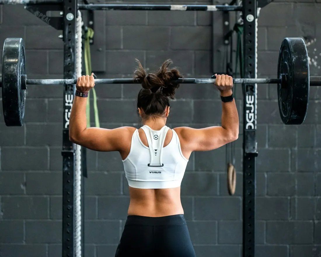 A lifter pressing a barbell overhead at a rack